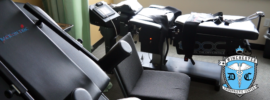 A doctor is adjusting the spinal decompression table's strap before engaging a patient with treatment.