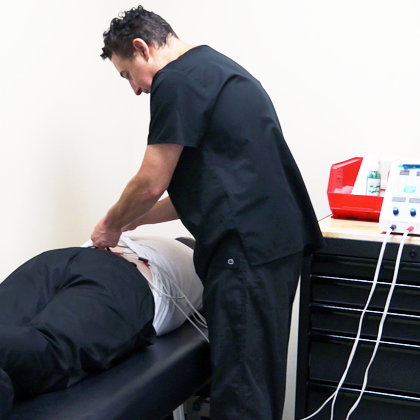 A patient is receiving stimulation on the lower back to prep for a chiropractic procedure.
